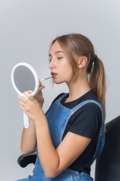 Young beautiful woman lipstick with an applicator looking in mirror.