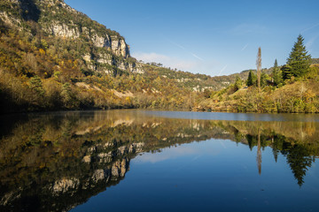 Fototapeta premium Reflets des falaises et des bois à la surface de l'eau de la rivière d'Ain.