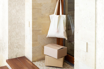 Bag with food on door handle. Contactless food delivery. Delivery boxes on porch near house. Safe shopping during coronavirus covid 19 quarantine. Charity donations in cotton shopping bag