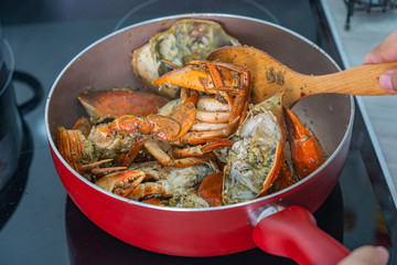 Closeup photo of human using spatula and cooking stir-fried crab