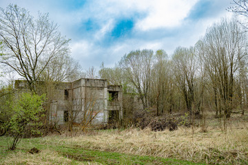 An old unfinished abandoned building from the times of the USSR in the forest, in early spring against the background of a beautiful sky. Atmospheric abandonment