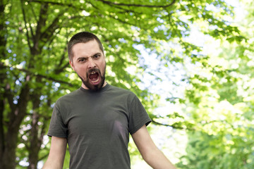 Naklejka na ściany i meble A bearded young man walks out of the park in anger. Emotional expression of anger