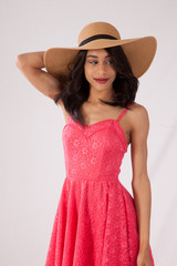 Happy Caucasian woman in a pink sun dress and a straw hat.