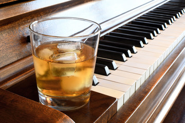 Glass of whisky close to a piano keyboard © Guy