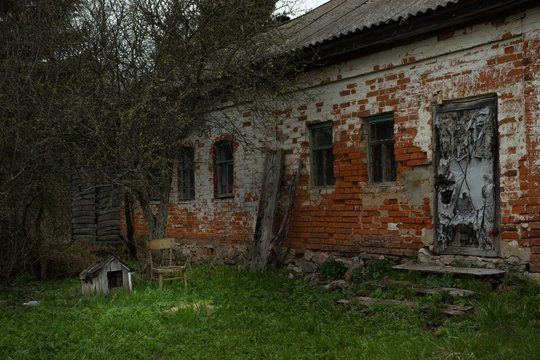 A brick abandoned old house in a deserted village, next to a doghouse - an illustration of a world without people.