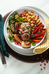 Italian Mediterranean Buddha bowl with Baba ghanoush caramelized onions, spicy chickpeas and grilled vegetables. healthy vegan food and pita bread