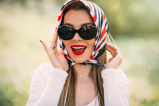 Surprised young girl with red lips in sunglasses and silk scarf