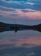 Fototapeta na wymiar Barge floats on the river Oka after sunset against the background of a purple sky