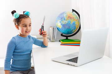 little girl learning hair cutting on laptop online