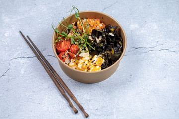 Hawaiian salmon fish poke bowl with rice, radish,cucumber, tomato, sesame seeds and seaweeds. Buddha bowl. Diet food