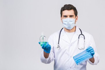 Doctor man in gown face mask gloves isolated on white background. Epidemic pandemic coronavirus 2019-ncov sars covid-19 flu virus. Bottle with alcohol liquid antibacterial sanitizer.
