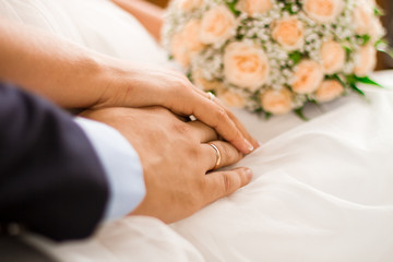 Obraz na płótnie Canvas Wedding ring on brides and husband hands with weddind bouquet.