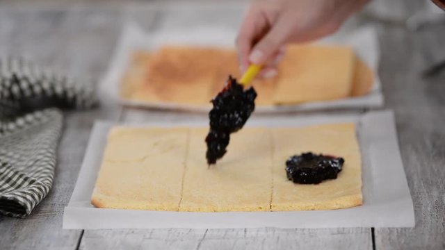 Girl spreading jam on a flat sheet of cake to make a cake with vertical layers at home.