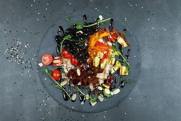 Hawaiian salmon fish poke bowl with rice, radish,cucumber, tomato, sesame seeds and seaweeds. Buddha bowl. Diet food