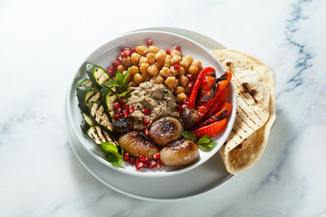 Italian Mediterranean Buddha bowl with Baba ghanoush caramelized onions, spicy chickpeas and grilled vegetables. healthy vegan food and pita bread