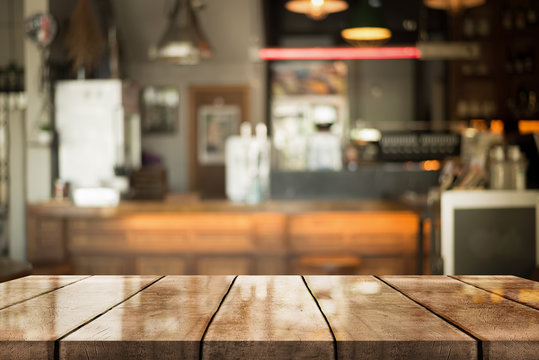 Empty old wood table top with bokeh coffee shop interior background.