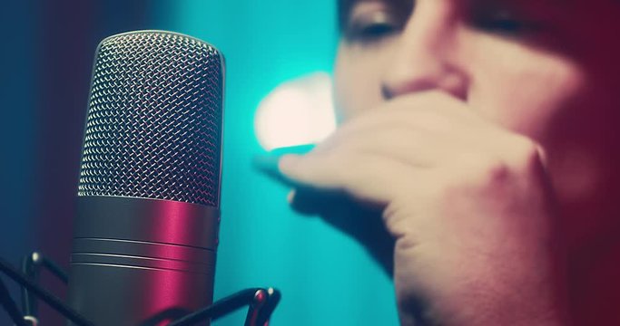 Close-up Musician in headphones playing on harmonica at home sitting on floor at evening time. Music hobby, Create own songs, learning online. Social distancing, 4K video
