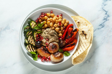 Italian Mediterranean Buddha bowl with Baba ghanoush caramelized onions, spicy chickpeas and grilled vegetables. healthy vegan food and pita bread