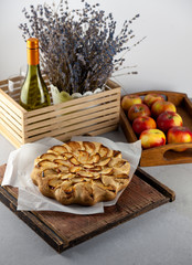 Apple pie and apples. Round homemade cake. Simple pastry made from shortcrust pastry and caramelized apple. Sweet pastries. Still life with lavender and a bottle of wine on the table.