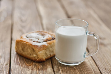 Basket of homemade buns with jam, served on old wooden table with cup of milk