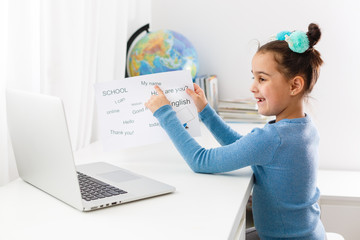 little girl learns english on laptop online