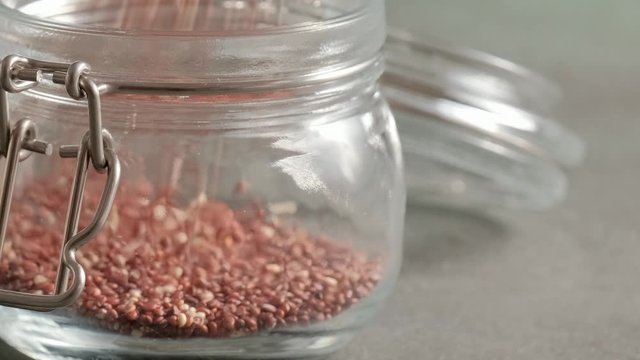 Red raw quinoa, South American grain, fall in glass jar. Healthy and gluten free food.
