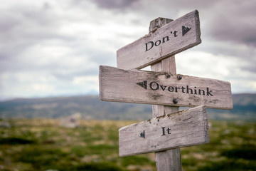 dont overthink it text engraved on old wooden signpost outdoors in nature. Quotes, words and illustration concept
