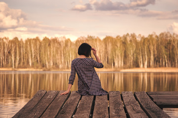 rear view of a young girl sitting on a pier