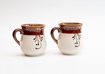 two beautiful decorated clay mugs isolated on a white background