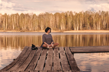 young girl sits on a pier in a summer dress