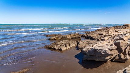 Rocky sea coast with blue water and small waves