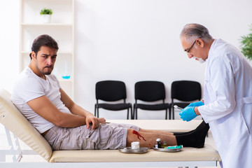 Leg injured man visiting old doctor in first aid concept