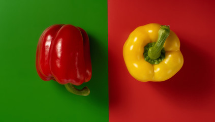 Red pepper on a green background and yellow pepper on a red background top view