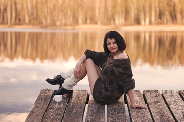 young girl with short hair sits on a pier in the summer