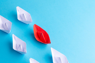 A red ship as a leader. White following it. Blue background. Place for text