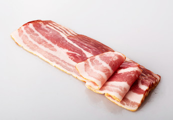bacon in slices and rolls with a sprig of fresh red Basil isolated on a white background
