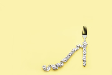 The fork lies on a colored background enquired by an inch. Proper nutrition, diet, place for text, view from above.