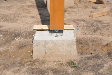 A close up on a wooden column, post anchored to concrete footing, foundation with bolts. © bildlove
