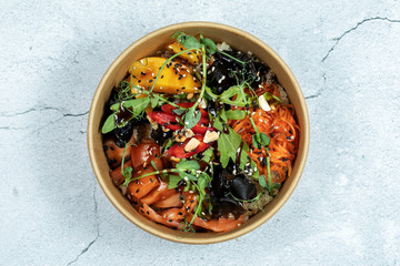 Hawaiian salmon fish poke bowl with rice, radish,cucumber, tomato, sesame seeds and seaweeds. Buddha bowl. Diet food