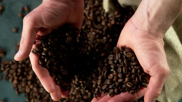 Super slow motion of male hands pouring coffee beans. Filmed on high speed cinema camera, 1000 fps.