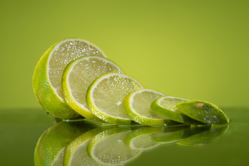 Waterfall of lime slices with green background.