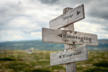 stop sabotaging yourself text engraved on old wooden signpost outdoors in nature. Quotes, words and illustration concept. - obrazy, fototapety, plakaty