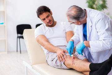 Obraz premium Leg injured man visiting old doctor in first aid concept