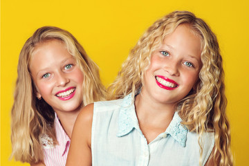 Lovely girls expressing positive emotions to camera. Sisters twins having fun together. Girls posing at studio.