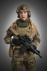 Female soldier in tactical black uniform with rifle. Shot in studio. Isolated with clipping path on grey background