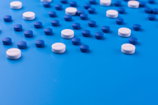 Medical background of white and blue pills on a blue background.Many sedative drugs.Copy space.