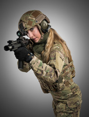 Female soldier in tactical black uniform with rifle. Shot in studio. Isolated with clipping path on grey background