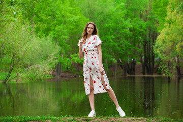 Portrait of a young beautiful woman in white dress posing by the lake