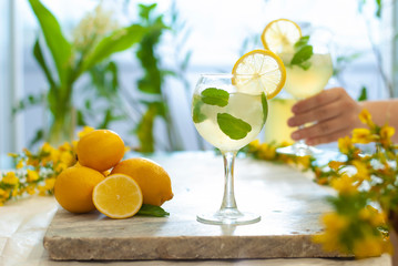 Citrus iced lemonade in pitcher and lemons glasses with lemon slice decoration and on marble table hand with cocktail