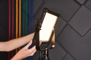 studio assistant fix professional video light on adjustable light stand. Led lamp on tripod in...